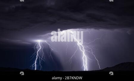 Powerful lightning bolt strikes from a dramatic thunderstorm cloud in the sky near Maricopa, Arizona Stock Photo