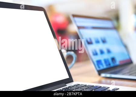 Mockup image of laptop with blank white desktop screen on wooden table in office Stock Photo