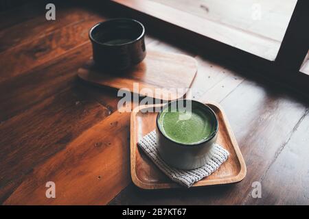 Two cups of hot matcha latte on wooden floor Stock Photo