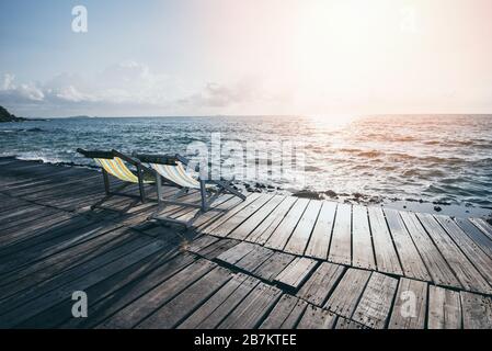 Terrace view of sea waves and coast landscape seascape rock with bench chair beach on wooden bridge balcony Tropical island with ocean blue sky and re Stock Photo