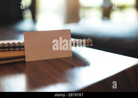 Closeup image of a white blank business card with notebooks on vintage wooden table Stock Photo