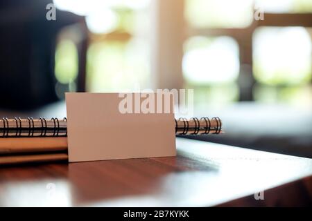 Closeup image of a white blank business card with notebooks on vintage wooden table Stock Photo