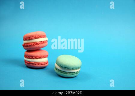 three macaroons of different colours on blue background. Image contains copy space Stock Photo
