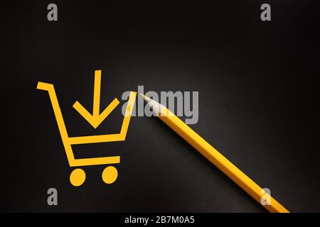 Yellow pencil with shopping cart on black background in buying shopping ecommerce concept Stock Photo
