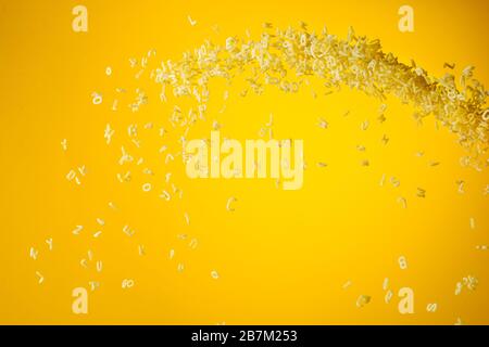 Zero gravity food concept. Flying uncooked pasta on yellow background with copy space. Stock Photo