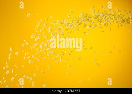 Concept of flying yellow raw italian pasta on yellow background with unfocused elements. Stock Photo