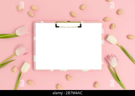 Clipboard mockup, easter eggs and flowers on a pink pastel background. Holiday concept with copy space. Stock Photo