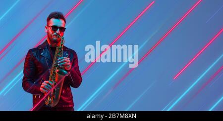 Creative emotions and neon lines on blue background, flyer, proposal. Caucasian young musician playing saxophone. Concept of human emotions, facial expression, sales, ad, music, hobby. Modern art. Stock Photo