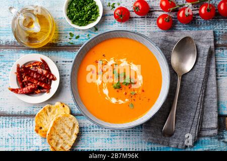 Pumpkin cream soup with fresh herbs in a bowl. Blue wooden background. Top view. Stock Photo