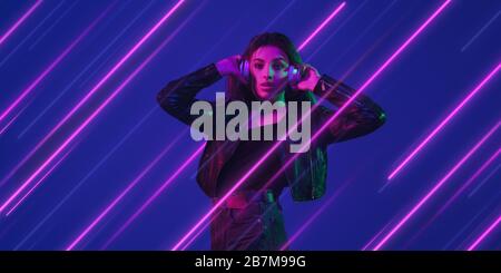 Creative emotions and neon lines on blue background, flyer, proposal. Caucasian young woman listen to music. Concept of human emotions, facial expression, sales, ad, music, hobby. Modern art. Stock Photo