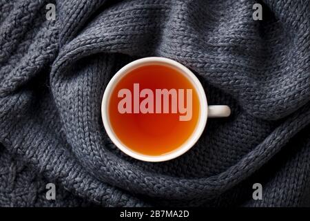 Cup of tea. Grey knitted scarf background. Top view. Stock Photo