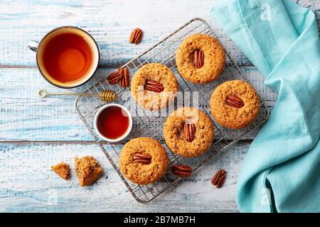 Pecan nut muffins on cooling rack with a cup of tea. Blue wooden background. Top view. Stock Photo