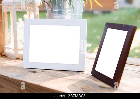 White and dark brown decorated photo frame with white background on outdoor wooden table. Stock Photo