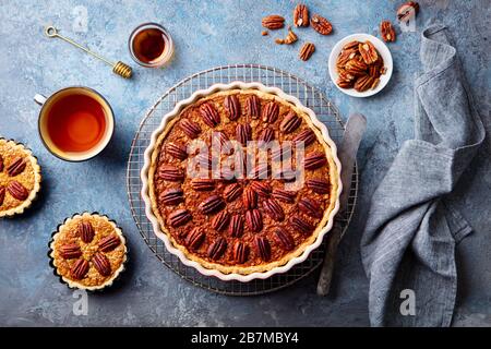 Pecan pie, tart in baking dish. Blue background. Top view. Stock Photo