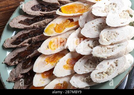Chicken rolls with dried apricots, prunes and mushrooms. Sliced. On a dark background. Copy space Stock Photo