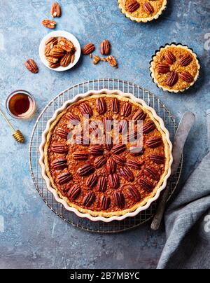 Pecan pie, tart in baking dish. Blue background. Top view. Stock Photo