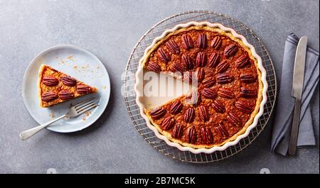 Pecan nuts pie, on a cooling rack. Grey background. Top view. Stock Photo