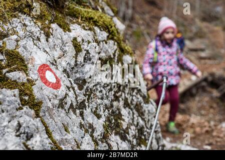 Children hiking in the mountains or woods on family trip. Focus on circular trail marker. Active family, parents and children mountaineering in the na Stock Photo