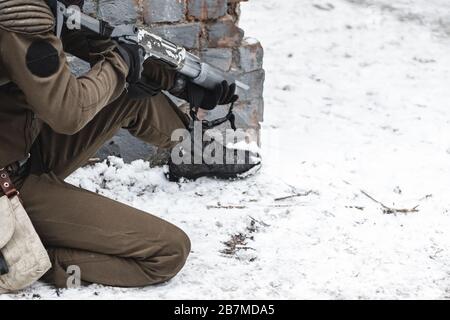 A military man with a shotgun squatting in ambush. Close up. Stock Photo