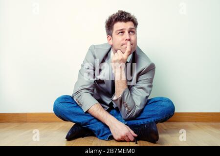 Portrait of a worried or concerned man or freelancer worker sitting legs crossed at home Stock Photo
