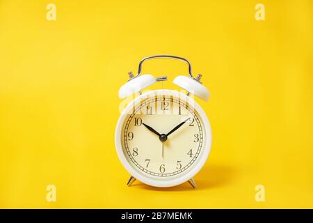 White alarm clock on a yellow background. Stock Photo