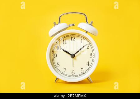 White alarm clock on a yellow background. Stock Photo