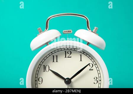 White alarm clock on a blue background. Close-up Stock Photo