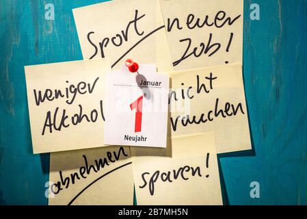 Note with good resolutions on a wall with a calendar page showing the first of January. Stock Photo
