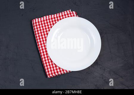 Empty white plate and red napkin on black table. Stock Photo