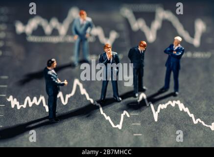 Businessmen stand on charts with falling stock prices Stock Photo