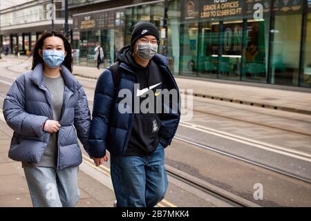 People wearing protective masks in Manchester, the day after Prime Minister Boris Johnson called on people to stay away from pubs, clubs and theatres, work from home if possible and avoid all non-essential contacts and travel in order to reduce the impact of the coronavirus pandemic. Stock Photo