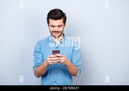 Portrait of handsome young man looking at his phone and smiling, he got message from his girlfriend Stock Photo