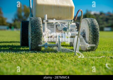 Lining a football pitch using white paint on grass Stock Photo