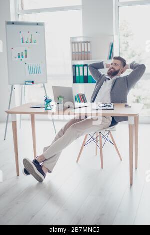 Vertical photo of satisfied happy young bearded man in formalwear having a rest while sitting on a chair and leaning on it's back Stock Photo