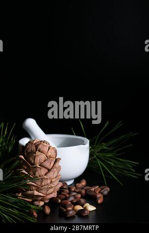 natural production concept, pine cone with nuts and mortar on a black background Stock Photo