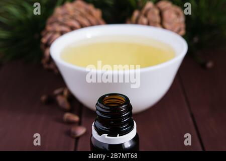 Cedar oil in a glass bottle and cedar cones with nuts on a old wooden table. Stock Photo