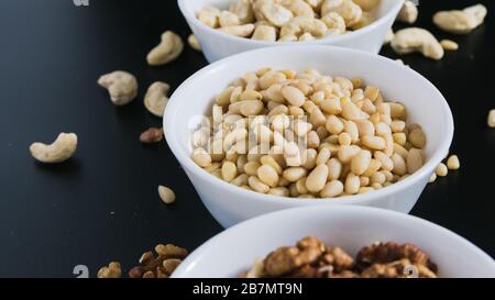 superfood concept, cedar, walnuts, cashew nuts in a plate on a black background Stock Photo