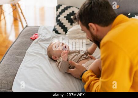 Father and baby.Young dad is changing baby diaper.Happiness and harmony in family life.Family, love,happiness and people concept. Stock Photo
