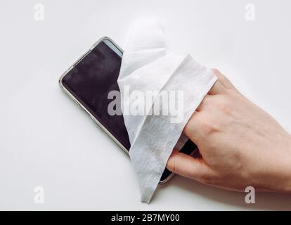 Close up view of man hand using antibacterial wet wipe for disinfecting smartphone touch screen. Stock Photo