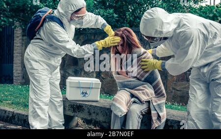 Doctors in protection suits caring for a woman Stock Photo