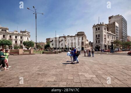 Lima, Peru - April 18, 2018: Tourists walking and talking in Plaza San Martin with gardens and buildings including Hostal San Martin in background. Stock Photo