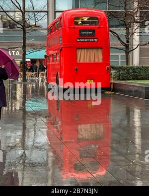 A puppet theatre on a traditional London red bus reflects in the rain. Stock Photo