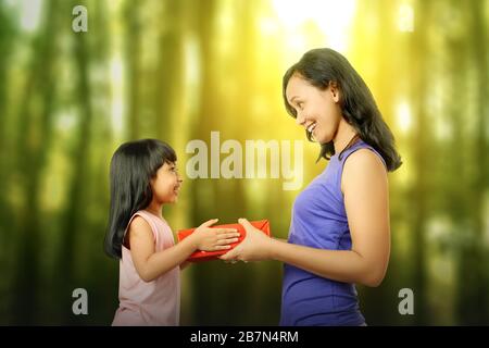 Mother's Day gift. Happy asian girl greeting young surprised mom, giving  her handmade card and wrapped gift box Stock Photo - Alamy