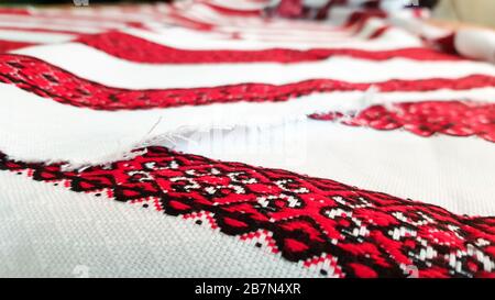 Ukrainian folk hand embroidery. Embroidered ornament with red-black threads on white fabric. Embroidered ornament in black and red thread. Ethnic Stock Photo