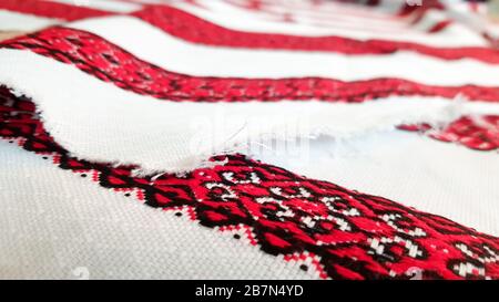 Ukrainian folk hand embroidery. Embroidered ornament with red-black threads on white fabric. Embroidered ornament in black and red thread. Ethnic Stock Photo