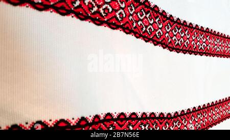 Ukrainian folk hand embroidery. Embroidered ornament with red-black threads on white fabric. Embroidered ornament in black and red thread. Ethnic Stock Photo