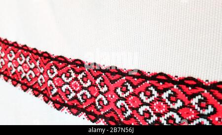 Ukrainian folk hand embroidery. Embroidered ornament with red-black threads on white fabric. Embroidered ornament in black and red thread. Ethnic Stock Photo