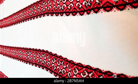 Ukrainian folk hand embroidery. Embroidered ornament with red-black threads on white fabric. Embroidered ornament in black and red thread. Ethnic Stock Photo