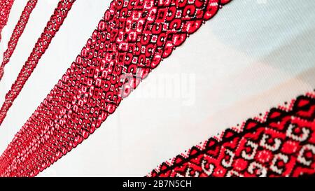 Ukrainian folk hand embroidery. Embroidered ornament with red-black threads on white fabric. Embroidered ornament in black and red thread. Ethnic Stock Photo