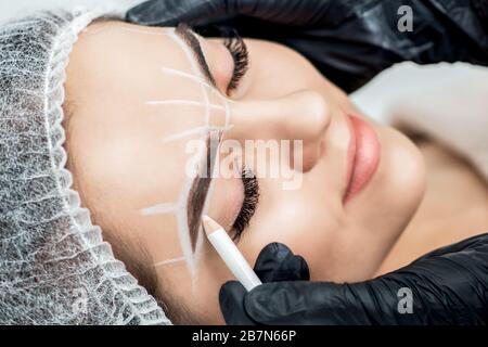 Markup with pencil on eyebrows of yong woman while permanent make up. Stock Photo